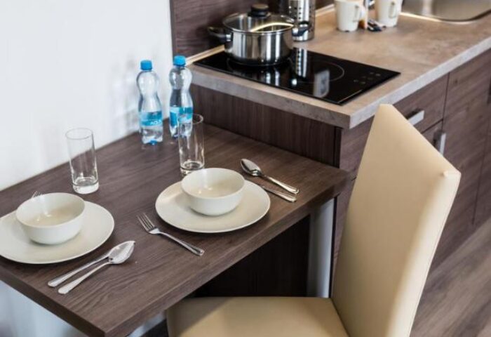 Hotel Residence Spalena's kitchenette. Gay-friendly hotel with dining table set for two, bottles of water, and cooking facilities.