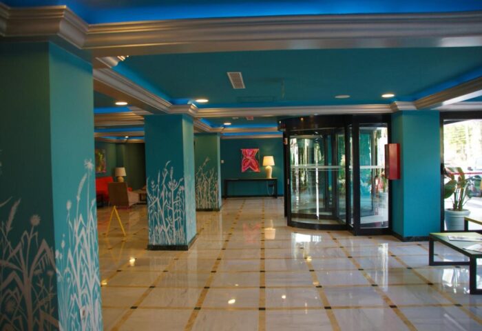 Hotel Ritual Torremolinos Adults Only lobby. Gay-friendly hotel with revolving door, turquoise walls, and white floral design. Modern, stylish interior.