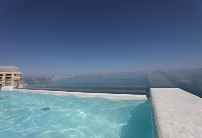 Hotel Ritual Torremolinos Adults Only gay-friendly hotel swimming pool. Clear blue sky above the pool and ocean view. Gay travel destination.