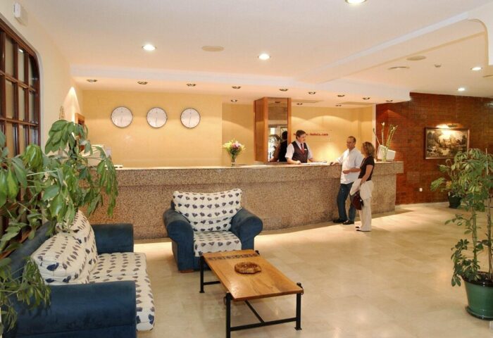 AluaSun Flamingo Hotel reception area. Gay-friendly hotel lobby with staff, seating, and clocks. A welcoming space for LGBTQ+ travelers.