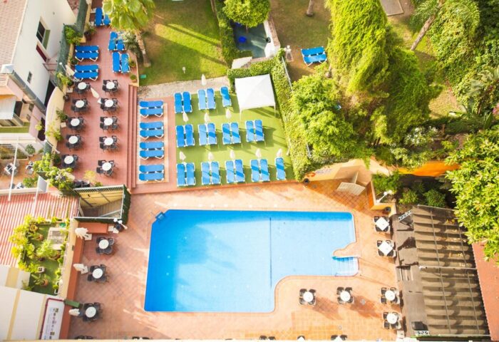 Aerial view of AluaSun Flamingo, a gay-friendly hotel. Pool, sunbeds, tables, and lush greenery create a relaxing atmosphere for gay travelers.