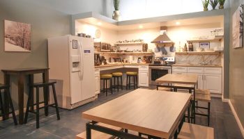 Hotel Royal's gay-friendly kitchen: a well-equipped space with tables, chairs, a refrigerator, and cooking facilities, perfect for guests.