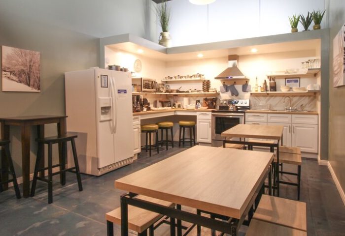 Hotel Royal's gay-friendly kitchen: a well-equipped space with tables, chairs, a refrigerator, and cooking facilities, perfect for guests.