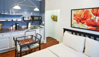 Hotel Royal gay-friendly room with kitchenette, bed, and floral art. A comfortable stay for gay travelers seeking welcoming accommodations.