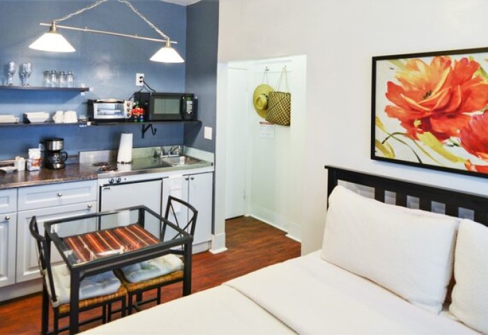 Hotel Royal gay-friendly room with kitchenette, bed, and floral art. A comfortable stay for gay travelers seeking welcoming accommodations.