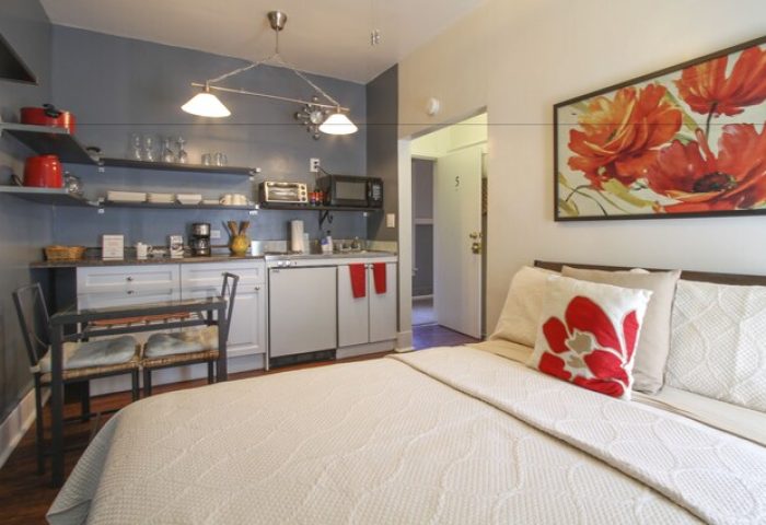 Hotel Royal gay-friendly room. Studio apartment interior with bed, kitchenette, dining table, and floral art. Gay travel lodging.