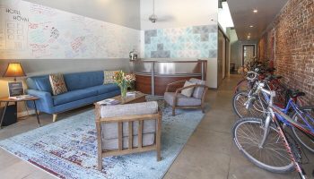 Hotel Royal's lobby, a gay-friendly hotel. Features a blue sofa, modern reception desk, and bikes. Welcoming space for gay travelers.