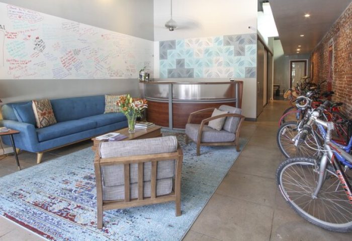 Hotel Royal's lobby, a gay-friendly hotel. Features a blue sofa, modern reception desk, and bikes. Welcoming space for gay travelers.
