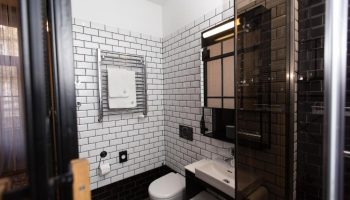 Hotel Rum Budapest bathroom. Gay-friendly hotel with white tiled walls, black accents, and a modern shower. Perfect for gay men travel.
