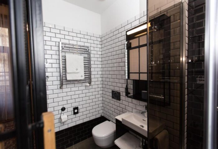 Hotel Rum Budapest bathroom. Gay-friendly hotel with white tiled walls, black accents, and a modern shower. Perfect for gay men travel.