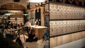 Hotel Rum Budapest's restaurant. Guests dine under modern lighting. Wine glasses line shelves. A gay-friendly hotel with a stylish bar.