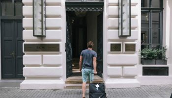 Man with luggage enters Hotel Rum Budapest. Gay-friendly hotel with modern design. Ideal for gay travelers seeking style and comfort.