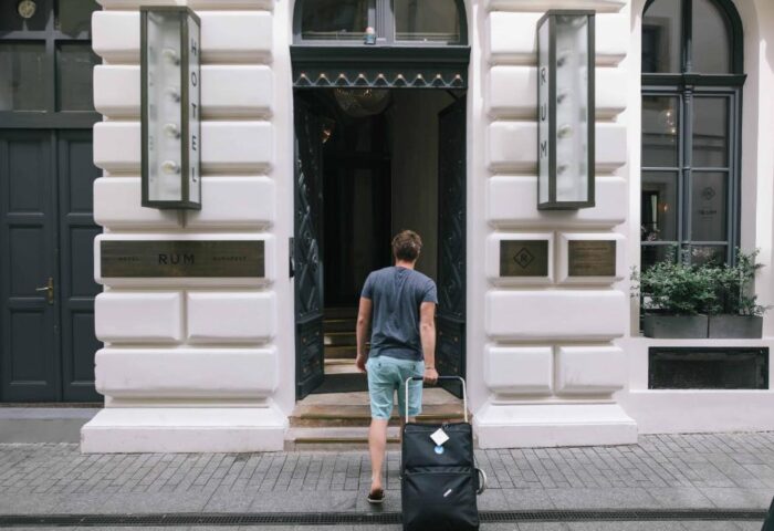 Man with luggage enters Hotel Rum Budapest. Gay-friendly hotel with modern design. Ideal for gay travelers seeking style and comfort.