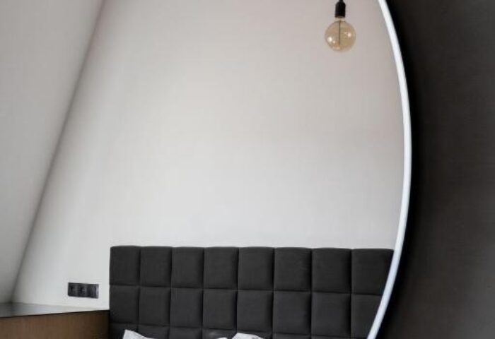 Hotel Rum Budapest, gay-friendly hotel room reflected in a mirror. Modern design with a bed, headboard, and hanging light bulbs.