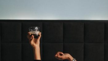 Hotel Rum Budapest: Guest in bed holding a drink. Gay-friendly hotel room with modern design. Relaxing travel experience in Budapest.