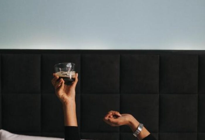 Hotel Rum Budapest: Guest in bed holding a drink. Gay-friendly hotel room with modern design. Relaxing travel experience in Budapest.