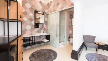 Hotel Rum Budapest gay-friendly bathroom. Modern design with patterned tiles, glass shower, sink, and chair. Stylish, comfortable stay.