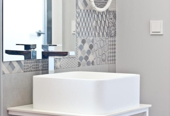 Hotel Ryans La Marina bathroom detail. Modern square sink, patterned tile backsplash, and hairdryer. Gay-friendly hotel amenities.