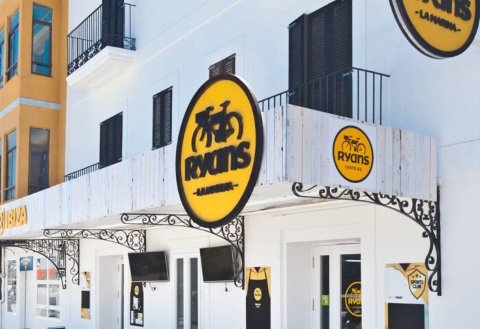 Hotel Ryans La Marina, a gay-friendly hotel in Ibiza. Exterior view of the hotel with outdoor seating, showcasing its modern design.