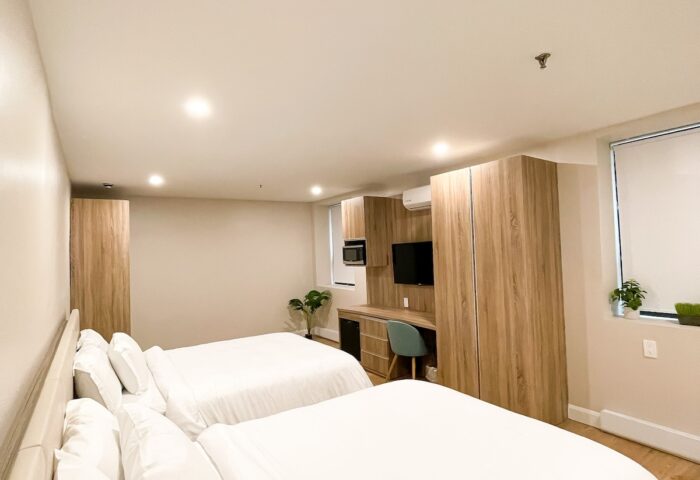 Hotel Saint-Andre gay-friendly room. Two beds with white linens, desk, TV, wood floors, and a window. Perfect for gay men travel.