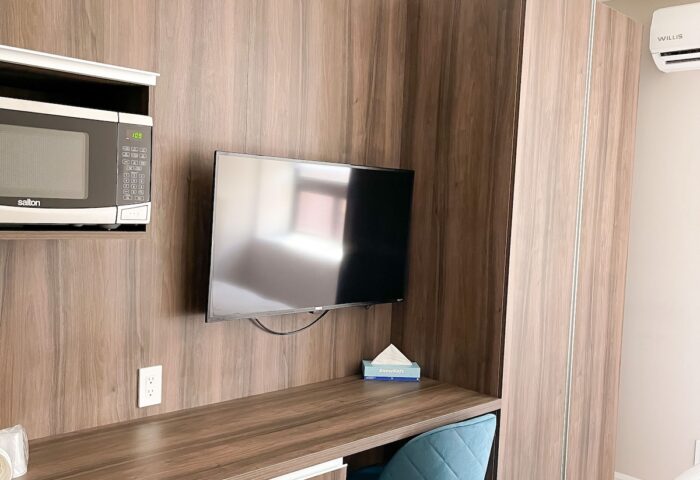 Hotel Saint-Andre detail. Gay-friendly hotel room with desk, microwave, TV, fridge, and blue chair. Modern design for gay travelers.