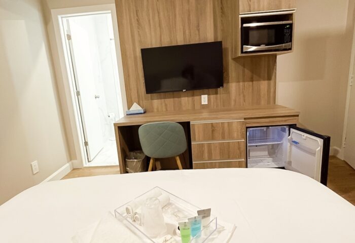 Hotel Saint-Andre gay-friendly room. Modern decor, TV, microwave, mini-fridge, and bathroom. Amenities tray on the bed. Comfy stay.