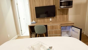 Hotel Saint-Andre gay-friendly room. Modern decor, TV, microwave, mini-fridge, and bathroom. Amenities tray on the bed. Comfy stay.