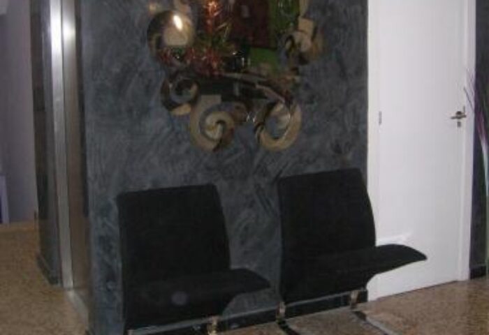 Hotel Santa Faz, adults only gay-friendly hotel. Two black chairs are placed against a decorative wall with a mirror. Interior design.
