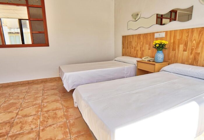 Hotel Santa Faz Adults Only, gay-friendly hotel room. Two twin beds, wood headboard, nightstand with flowers. Window and tile floor.