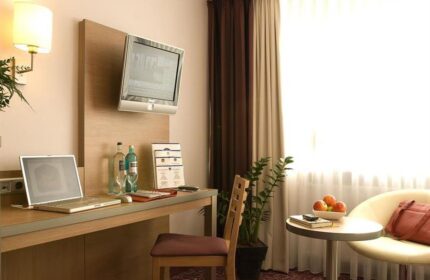 Gay-Friendly Hotel Scala room: desk with laptop, TV, chair, and table with fruit. Comfortable & modern for gay men travelers.