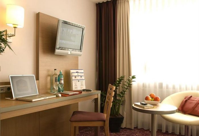 Gay-Friendly Hotel Scala room: desk with laptop, TV, chair, and table with fruit. Comfortable & modern for gay men travelers.