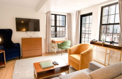 Hotel Scherman's gay-friendly room. Modern interior with armchairs, desk, and TV. A comfortable space for gay travelers to relax.