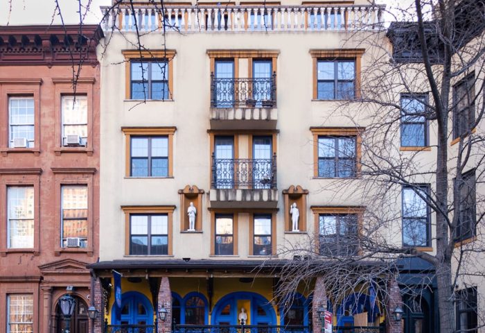 Hotel Scherman, a gay-friendly hotel. Building facade with blue and yellow accents. Balconies, statues, and architectural details.