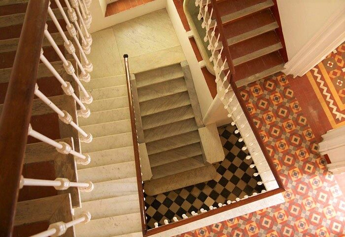 Staircase at Hotel Sitges 1883, a gay-friendly hotel. View from above showcases the tile flooring and marble steps. A historic detail.
