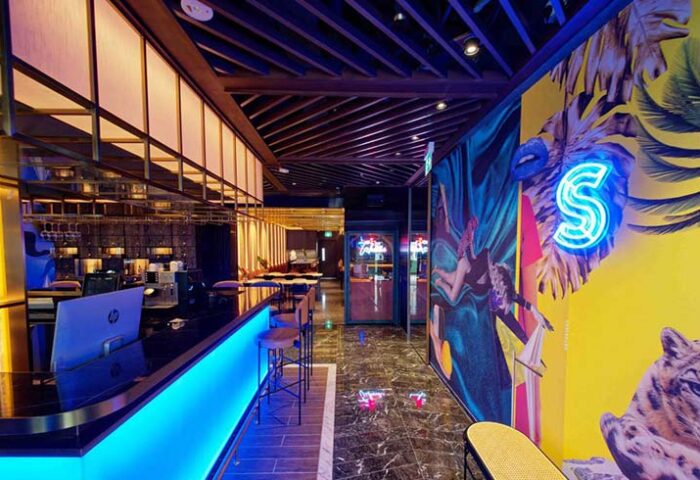 Hotel Soloha @ Chinatown bar area. Gay-friendly hotel with neon 'S' logo, vibrant mural, & stylish bar. A cool spot for gay men travelers.