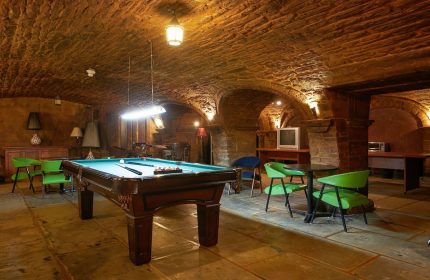 Hotel St-Denis gay-friendly hotel: Billiard room with stone walls and arched ceiling. Pool table, chairs, and tables for relaxing.