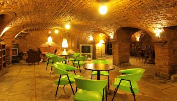 Hotel St-Denis's gay-friendly lounge area. Arched brick ceiling, green chairs, and warm lighting create a welcoming atmosphere for gay travelers.