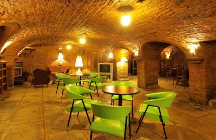 Hotel St-Denis's gay-friendly lounge area. Arched brick ceiling, green chairs, and warm lighting create a welcoming atmosphere for gay travelers.