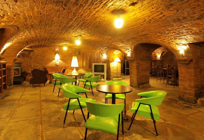 Hotel St-Denis's gay-friendly lounge area. Arched brick ceiling, green chairs, and warm lighting create a welcoming atmosphere for gay travelers.
