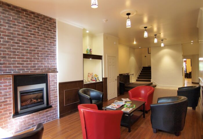 Hotel St-Denis's gay-friendly lounge area. Red and black armchairs surround a coffee table with magazines. A fireplace adds warmth.