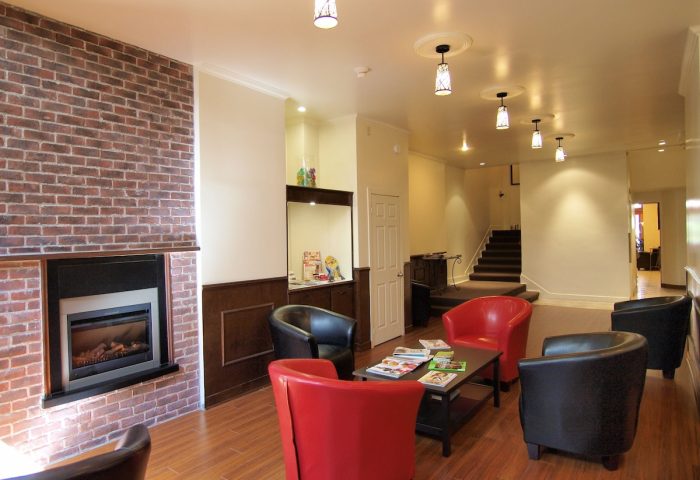 Hotel St-Denis's gay-friendly lounge area. Red and black armchairs surround a coffee table with magazines. A fireplace adds warmth.