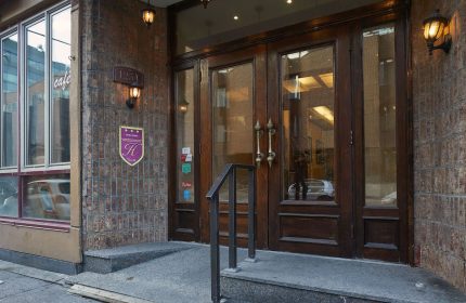 Hotel St-Denis entrance, a gay-friendly hotel. The facade features a brick wall, wooden doors, and a sign with the hotel's logo.