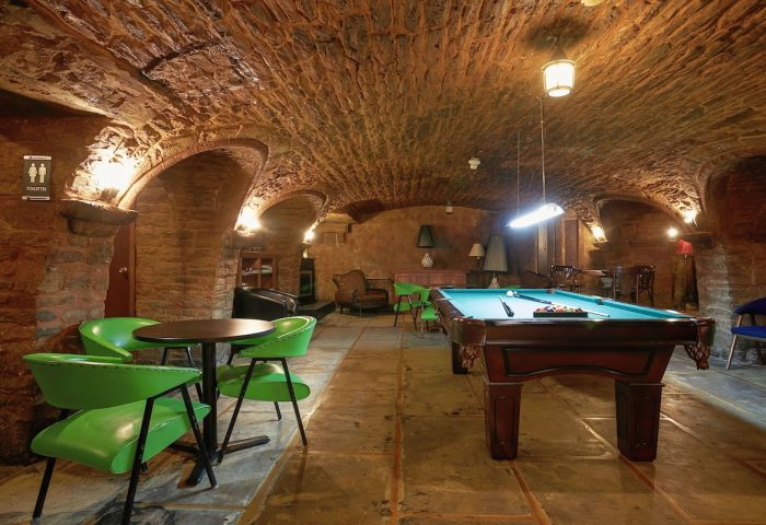 Hotel St-Denis' gay-friendly interior. Stone-walled game room with pool table, green chairs, and arched ceiling. Gay travel lodging.