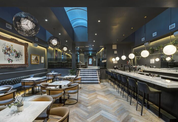 Hotel St. Thomas gay-friendly hotel interior. Bar with stools, tables, chairs, and art. Stylish design for gay men travel.