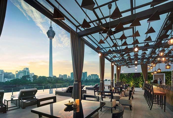 Hotel Stripes Kuala Lumpur Autograph Collection gay-friendly hotel. Rooftop bar view of KL Tower & city skyline at sunset.