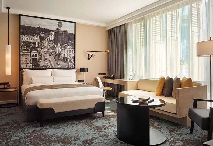 Hotel Stripes Kuala Lumpur, Autograph Collection guest room. Gay-friendly hotel with bed, sofa, desk, and city view art. Modern design.