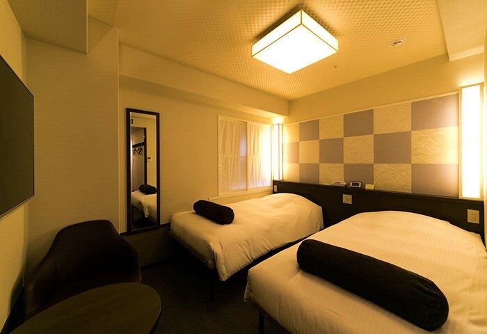 Hotel Sunlite Shinjuku gay-friendly hotel room with two beds, chair, and mirror. A comfortable stay in Shinjuku, Tokyo for gay travelers.