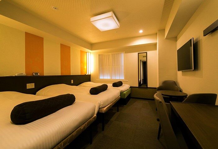 Hotel Sunlite Shinjuku's gay-friendly room with three beds, TV, desk, and chairs. A comfortable stay for gay travelers in Shinjuku, Tokyo.
