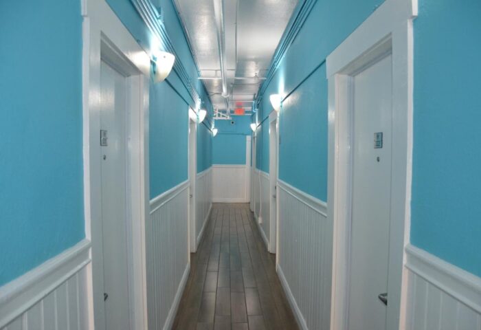 Hotel Sunrise's hallway. Gay-friendly hotel features bright blue walls, white trim, and wood-look floors. A welcoming space for gay travelers.