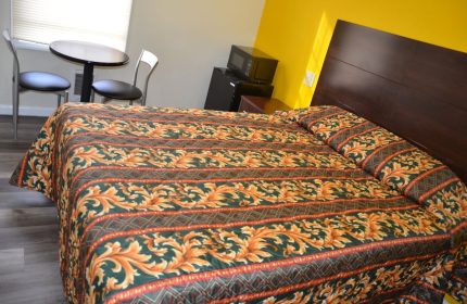 Hotel Sunrise gay-friendly room. Features a bed with patterned bedding, a small table with chairs, microwave, and mini-fridge.